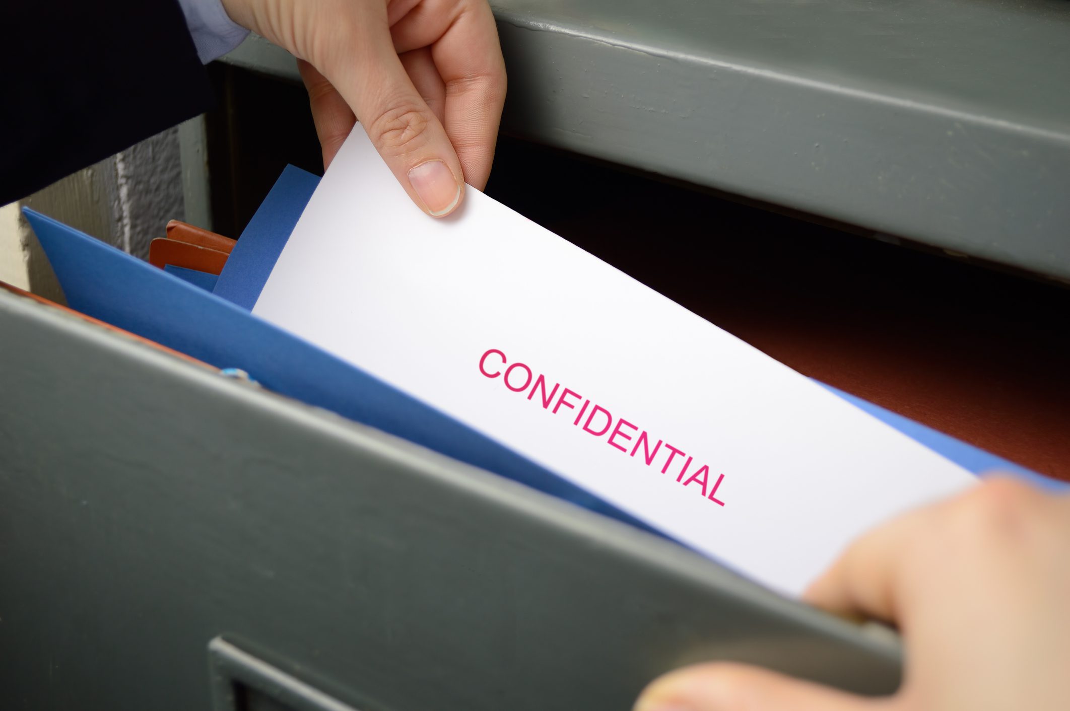 Hands carefully reaching for the confidential documents